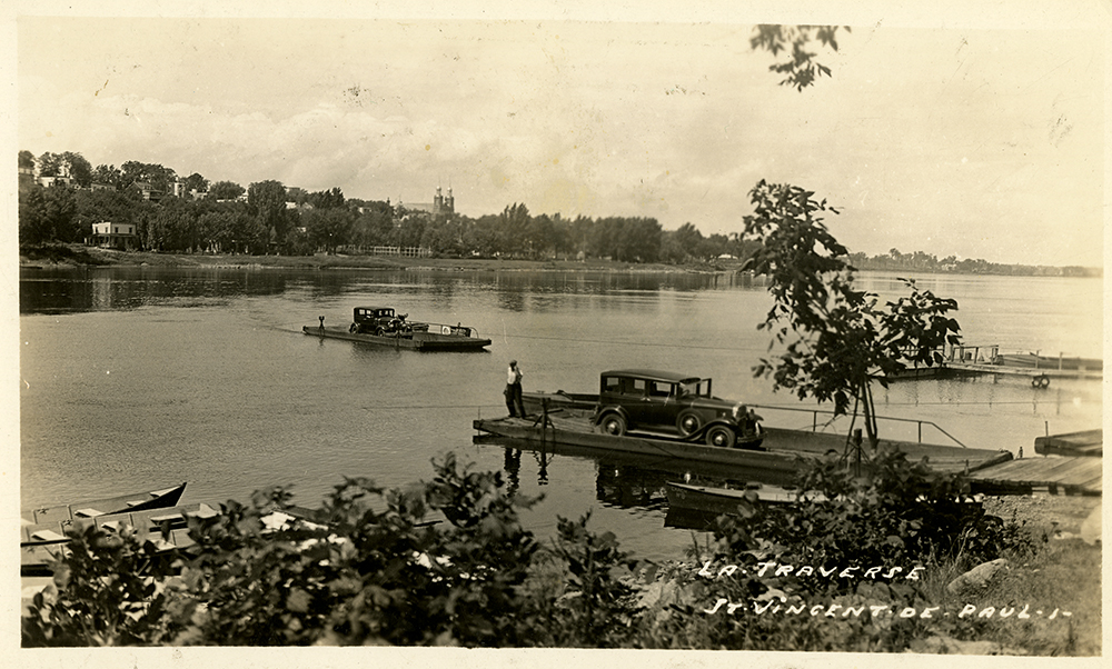 Photographie d’époque en teinte sépia. Elle montre deux voitures sur deux traverses à traille, reliant l’est de l’île Jésus et le village de Sault-au-Récollets sur l’île de Montréal. En bas à droite, il est écrit à la main : La traverse Saint-Vincent-de-Paul. 