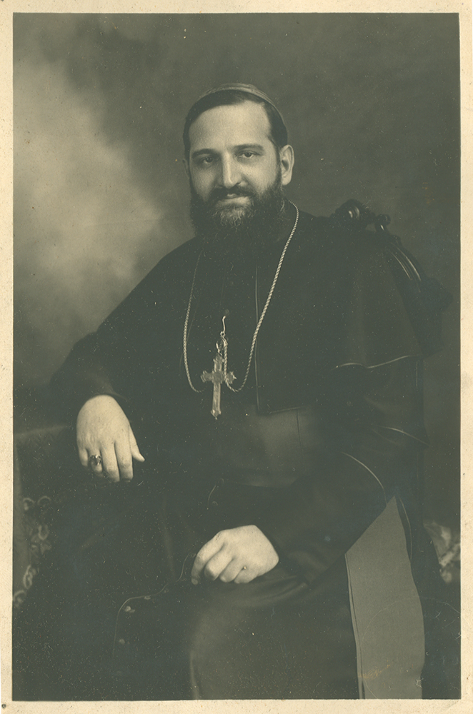 Photographie noir et blanc de Monseigneur Alfred LePailleur. Il est assis sur un fauteuil dans le décor d'un studio photo.