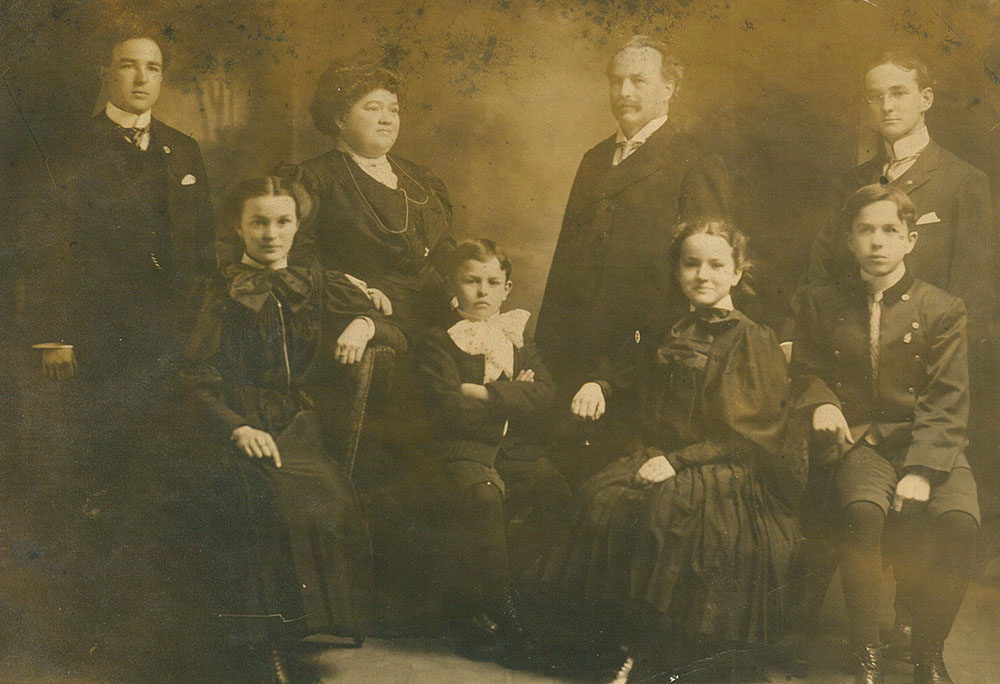 Photo de famille couleur sépia. En arrière-plan, se trouvent Théophile, Célina-Elmire, Joseph-Adélard senior et Joseph-Albert. En avant, les 4 enfants sont assis. Ce sont Aimée, Auguste, Marie-Rose et Joseph-Adélard Junior.