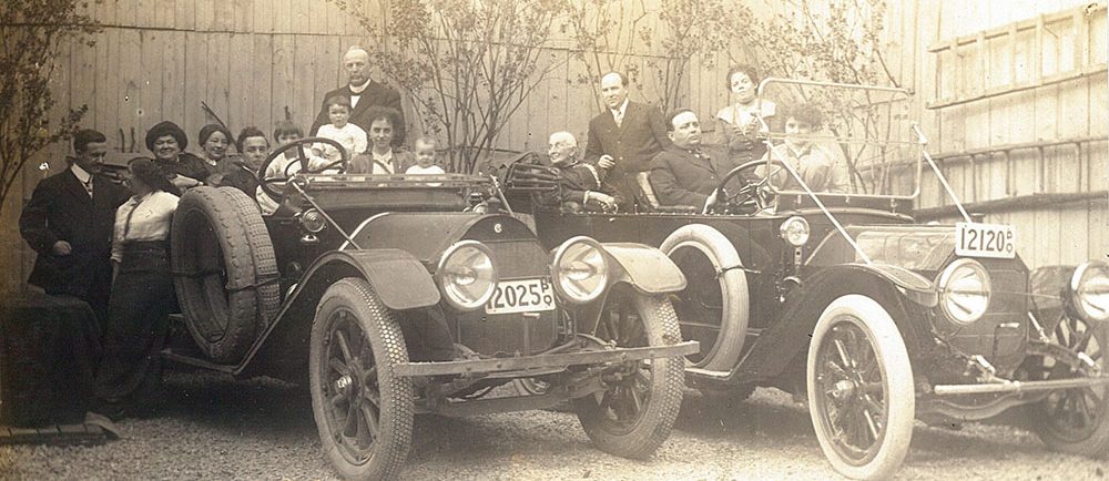 Photo noir et blanc d'un groupe de personnes assis dans 2 voitures des années 20. Dans le groupe se trouve, Théophile et Célina-Elmire LePailleur, Joseph-Adélard Descarries et Philomène Dalton. 5 personnes se tiennent debout au sol ou sur les marche-pieds des voitures.