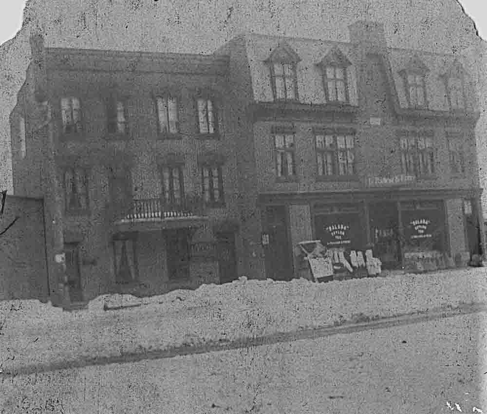 Photo noir et blanc de la façade du commerce LePailleur et  Frères. Il y a de la neige sur le chemin.