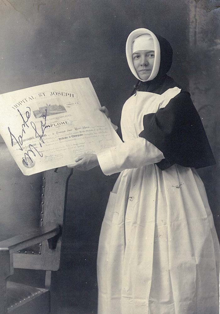 Photo noir et blanc de Soeur Marie-Louise LePailleur, en habit de religieuse des Soeurs de la Providence avec un tablier d’infirmière tenant son diplôme de garde-malade.