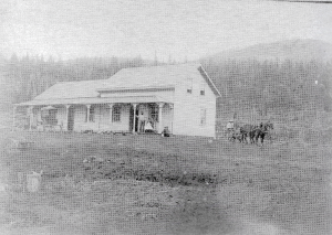 Maison en bois et charettes devant coline boisée