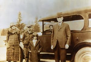 Homme, femme et 2 enfants devant une voiture d'époque