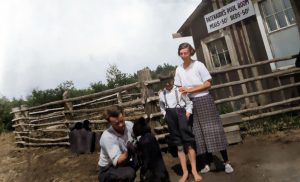 Famille de trois avec ourson devant cabane et clôture en bois