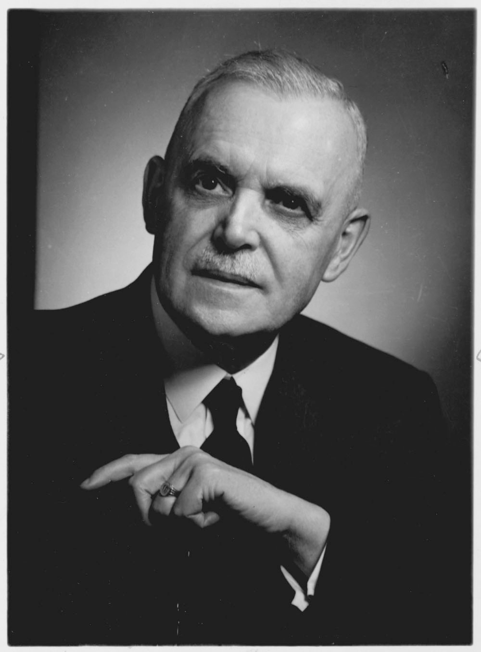Portrait noir et blanc plan buste du l’Honorable Louis St-Laurent en costume-cravate, son front marqué par un recul de la lisière de ses cheveux gris; ses yeux noirs lui donnant une expression autoritaire.