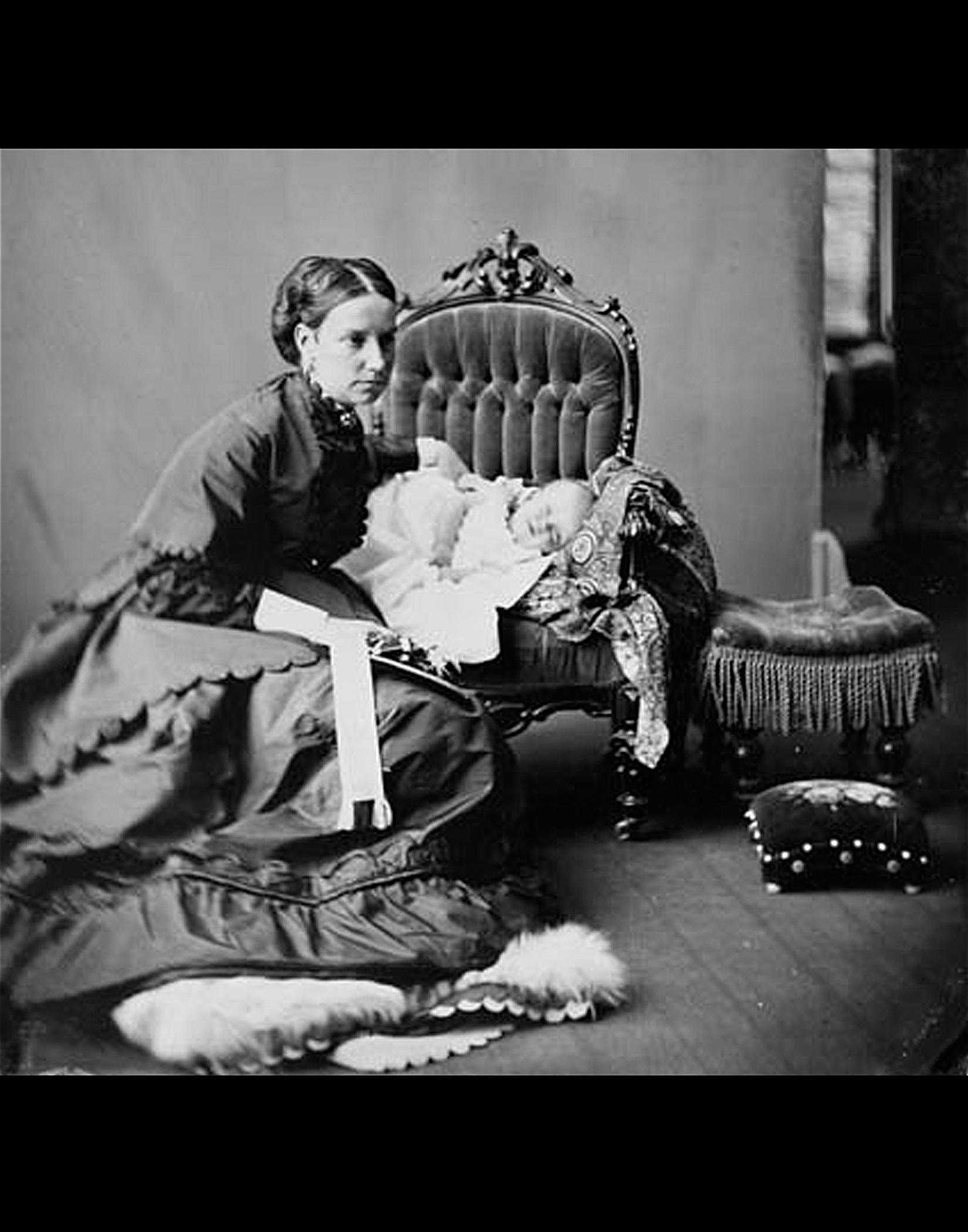 Photo noir et blanc de Lady Agnes Macdonald accroupie à côté d’une chaise sur laquelle repose son bébé, la petite Mary, en 1868. 
