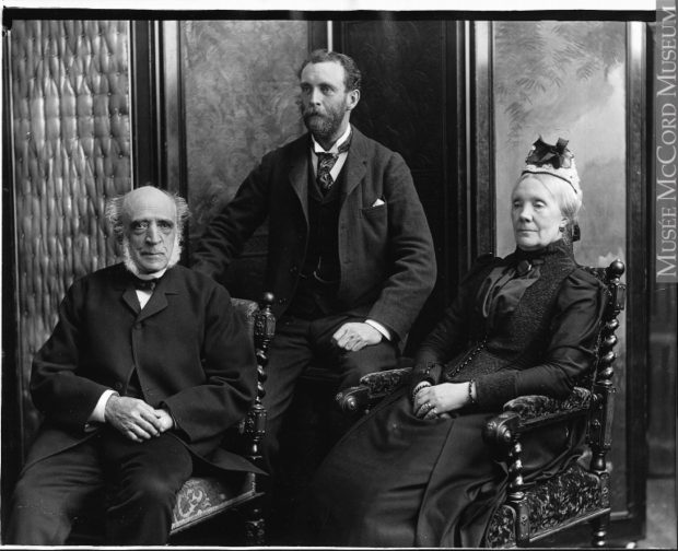 Photo officielle en noir et blanc de trois personnes (William C. Meredith, son épouse, Sofia Naters Holmes Meredith et leur fils, Henry Meredith); le couple (âgé) assis sur des chaises richement sculptées et leur fils assis derrière eux sur un tabouret. 