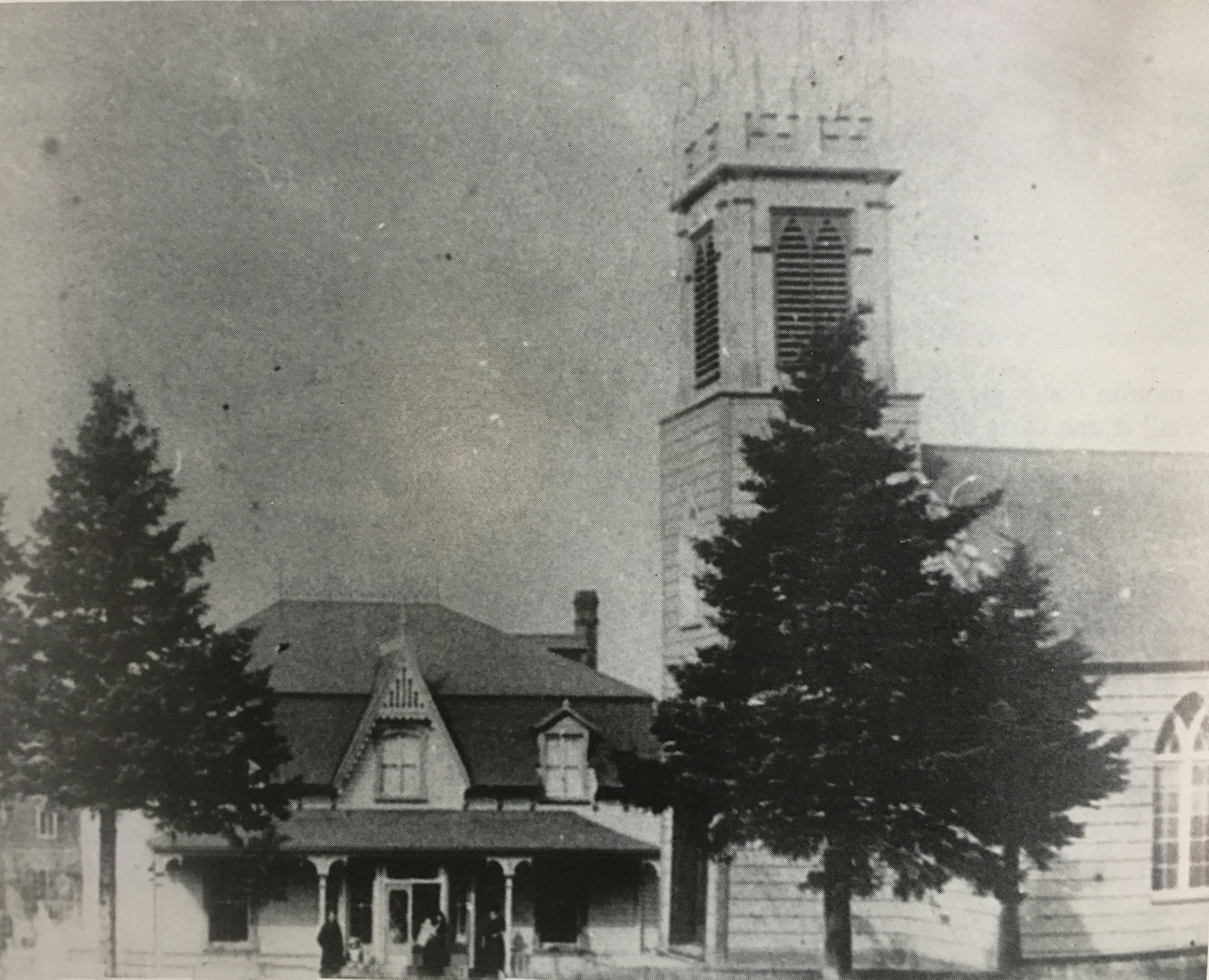 Photo noir et blanc d'une vieille église en bois, l'église anglicane St. Bartholomew surmontée d’un clocher en façade et de son presbytère à deux étages attenant.