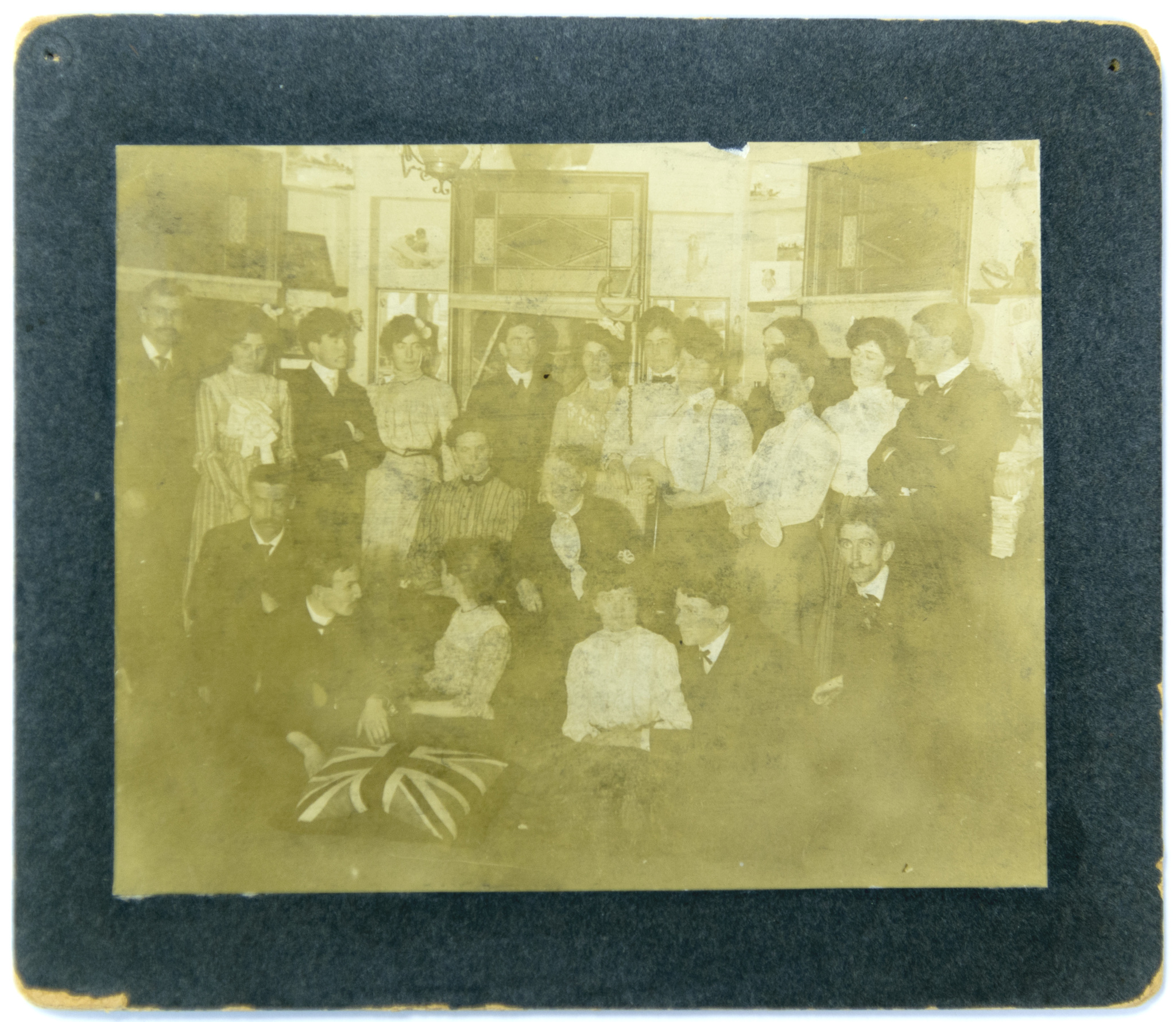 Image d’un large groupe de personnes en tenue de soirée rassemblées à l’intérieur d’une pièce avec des photos au mur.
