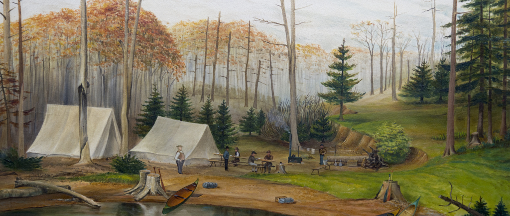 Tableau d’hommes rassemblés à un terrain de camping avec des canoës au premier plan et plusieurs grands arbres à l’arrière-plan.