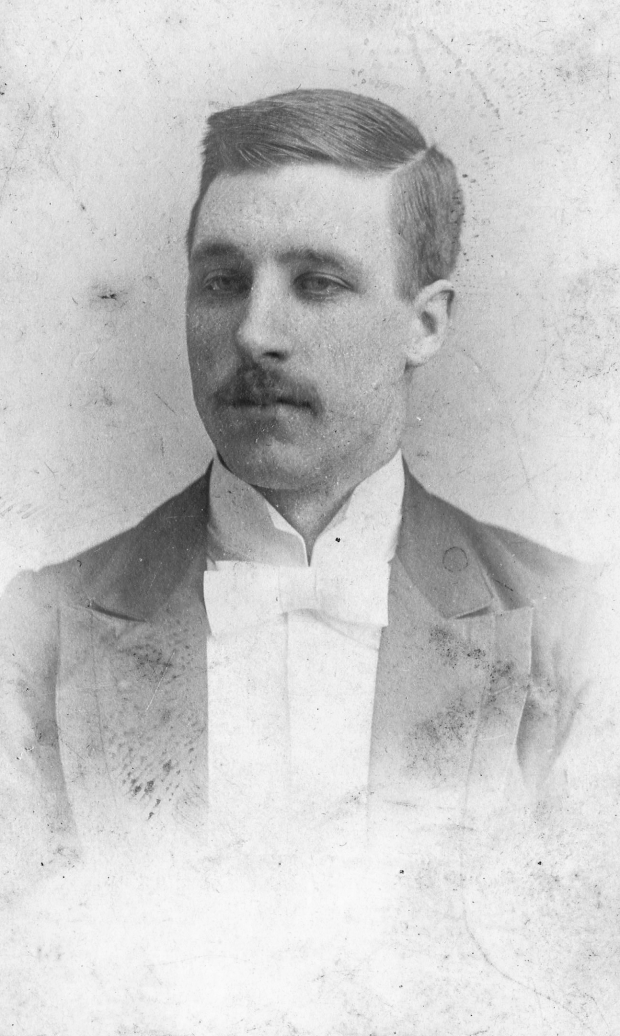 Photographie d’archive en noir et blanc d’un homme en costume et nœud-papillon.
