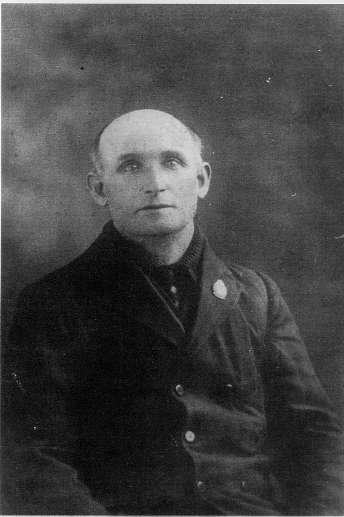 Photographie d’archive en noir et blanc d’un homme à la calvitie débutante portant un pardessus.