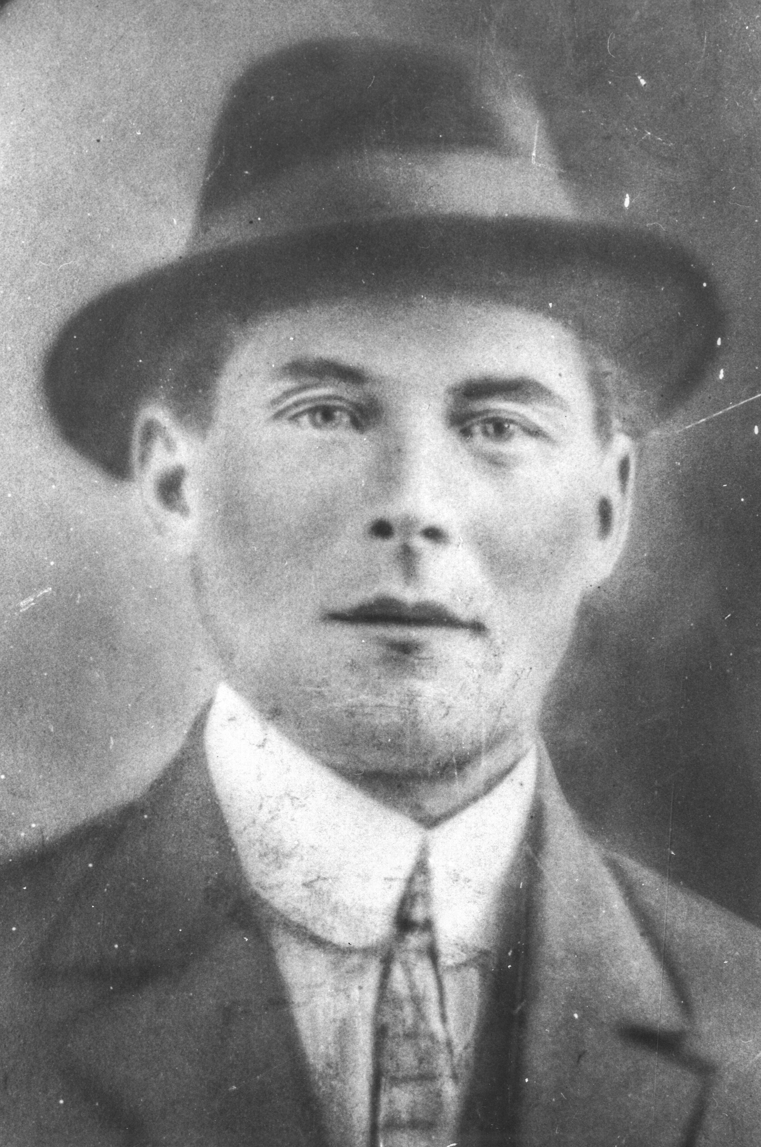 Photographie d’archive en noir et blanc d’un homme portant un feutre mou et un costume-cravate.