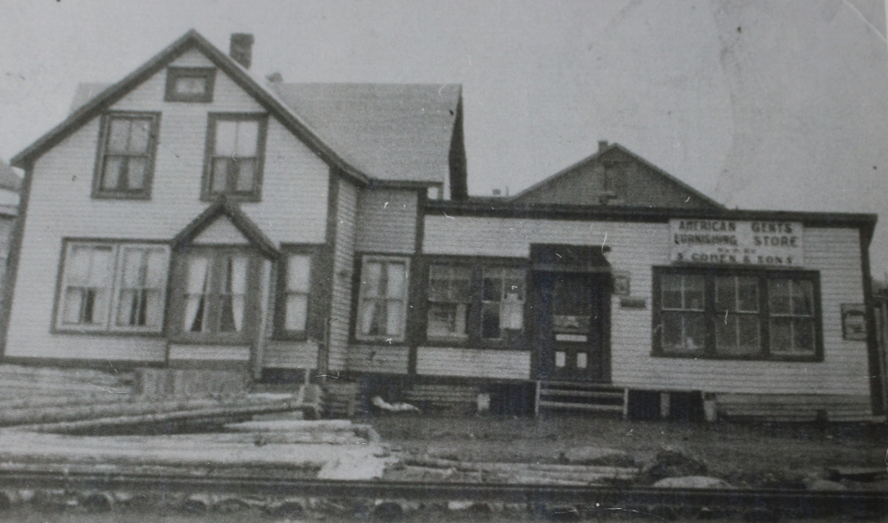 Photographie d'archives en noir et blanc. Vue de la rue. Vue extérieure du magasin American Gents Furnishing Store S. Cohen & Fils de la rue Main.