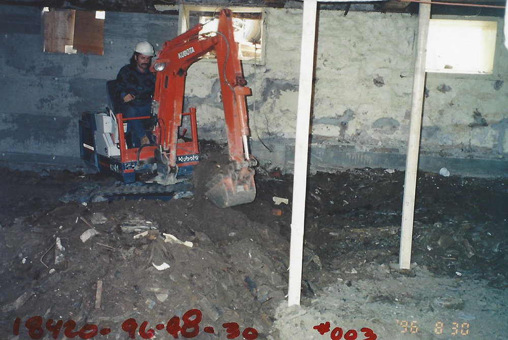 Photo couleur. Ouvrier creusant le sous-sol du Manoir à l'aide d'une excavatrice.