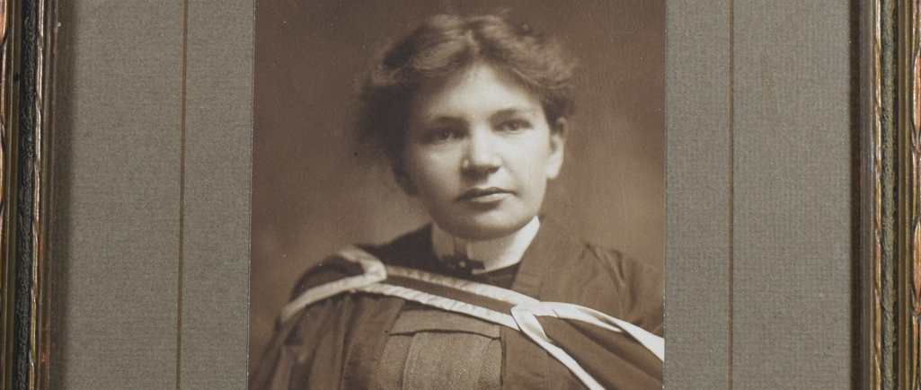 Photographie en noir et blanc de Maude Abbott, jeune adulte, de la taille à la tête. Elle porte un habit et une toge de graduation. Ses cheveux foncés sont attachés à l’arrière de sa tête et sa tête est légèrement tournée vers la gauche. Dans le coin inférieur droit, une signature à l’encre : « Sincerely Yours. Maude Elizabeth Seymour Abbott ». Un peu plus bas, la signature de l’imprimeur, « Rice. Montreal ». 