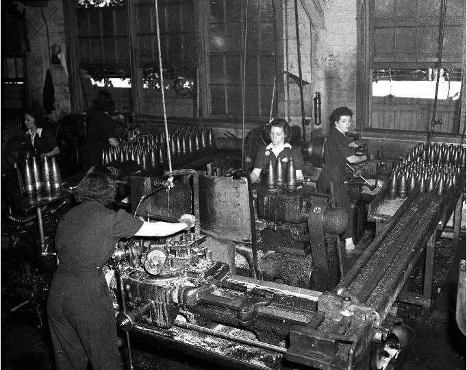 Des ouvrières opèrent des machines dans une manufacture d’obus.  