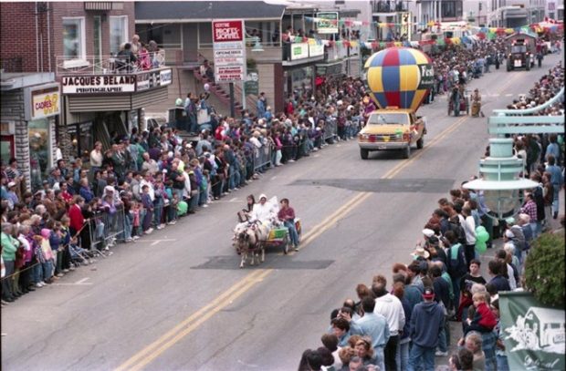 Au Festival de la galette de sarrasin à Louiseville, une parade a lieu. Un char allégorique tiré par un poney parade sur la rue principale alors que des personnes des deux côtés de la rue l’observent.