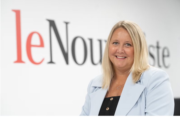 Photographie en couleur de Julie Michaud devant un fond comportant le titre du journal Le Nouvelliste. 