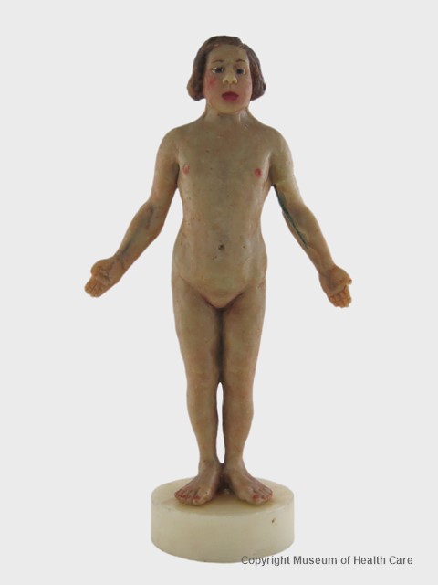 Photo en couleur du modèle en cire d'une femme nue se tenant debout les bras ouverts. 