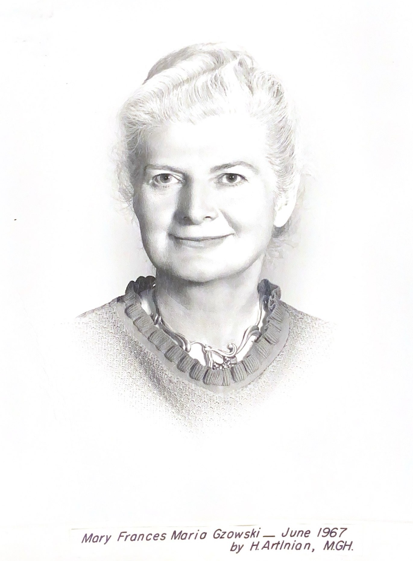 Portrait en noir et blanc d'une femme aux cheveux blancs bien coiffés, vêtue d'un chandail et portant un collier. 