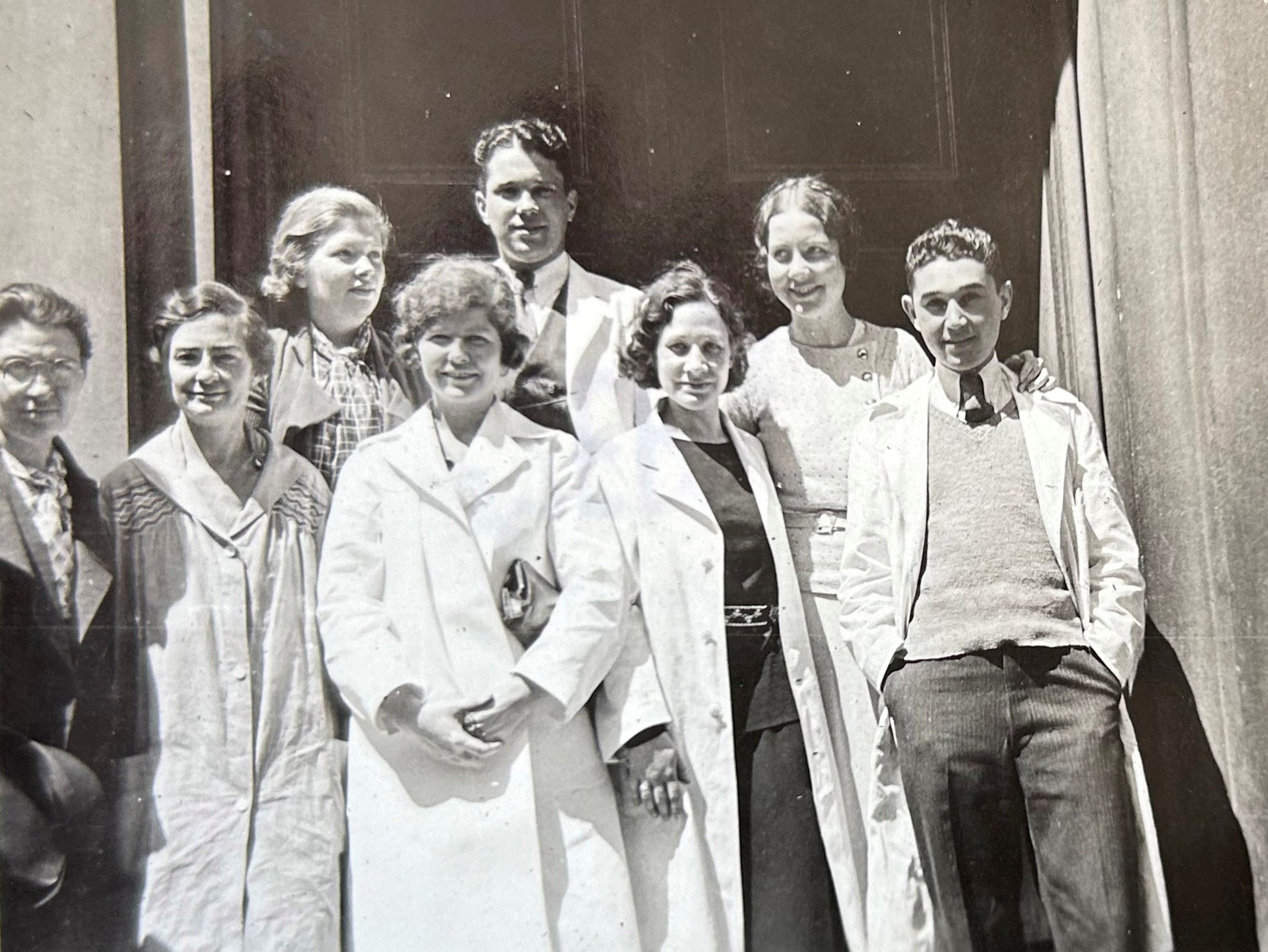 Photo en noir et blanc de huit élèves posant en deux rangées, vêtus de blouses de laboratoire. 