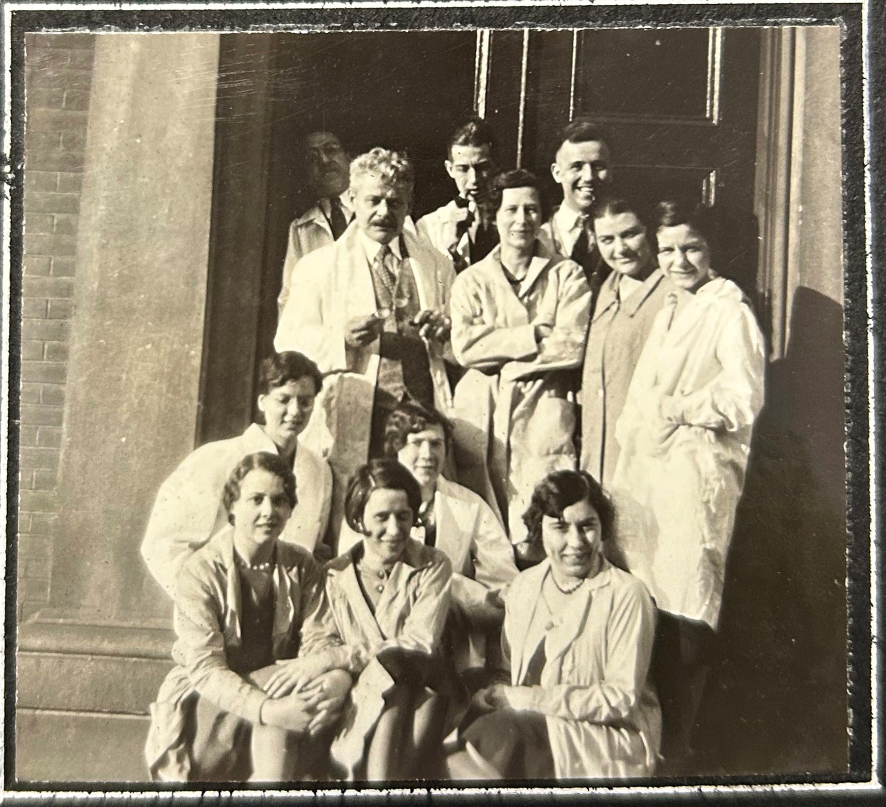 Photo en noir et blanc d'un groupe d'élèves de tous genres portant des blouses de laboratoire et posant en rangées. 