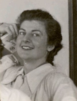 Photo en noir et blanc d'une femme souriant à l'appareil photo, la main appuyée contre sa tête, tenant ce qui semble être un étui à cigarettes.