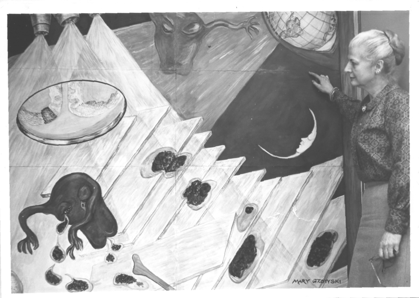 Photo en noir et blanc de Mary Gzowski contemplant une murale dépeignant un utérus caricatural volant dans l'espace. 