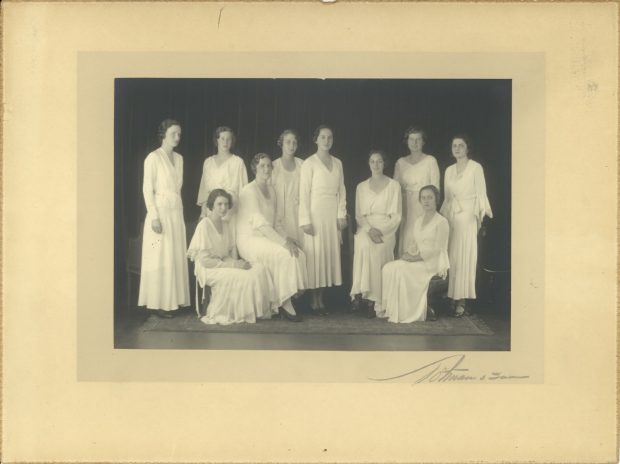 Photo en tons sépia de dix jeunes femmes vêtues de blanc, certaines assises, d'autres debout.