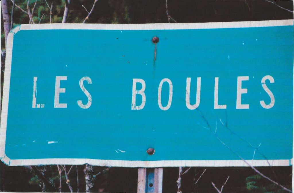 Photographie couleur du panneau routier présentant le village de Les Boules.