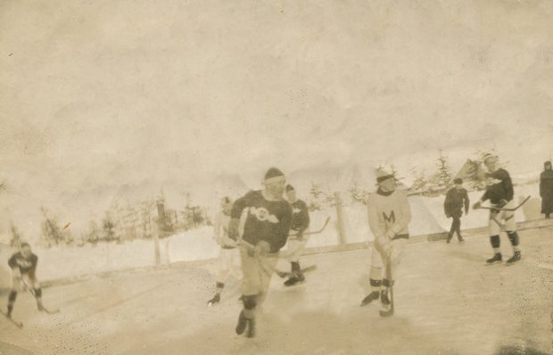 Image sépia de cinq jeunes joueurs de hockey sur une patinoire extérieure à Métis.