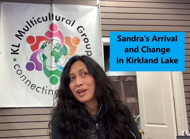 Sandra Reygada Licuime est assise devant le panneau du groupe multiculturel de Kirkland Lake, face à la caméra.