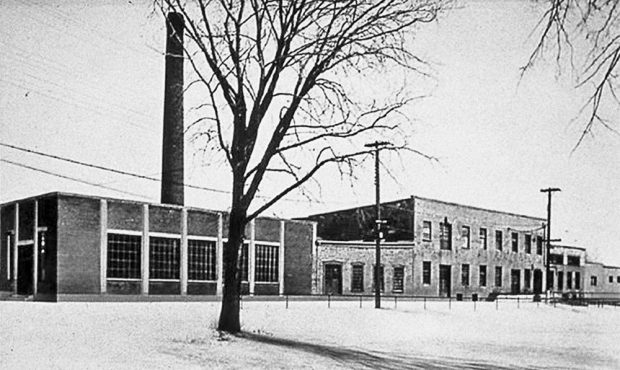 À gauche, derrière un arbre planté sur l’île de la Visitation, l’entrepôt et la cheminée de la Back River Power Company. À leur droite, son usine sur la digue.