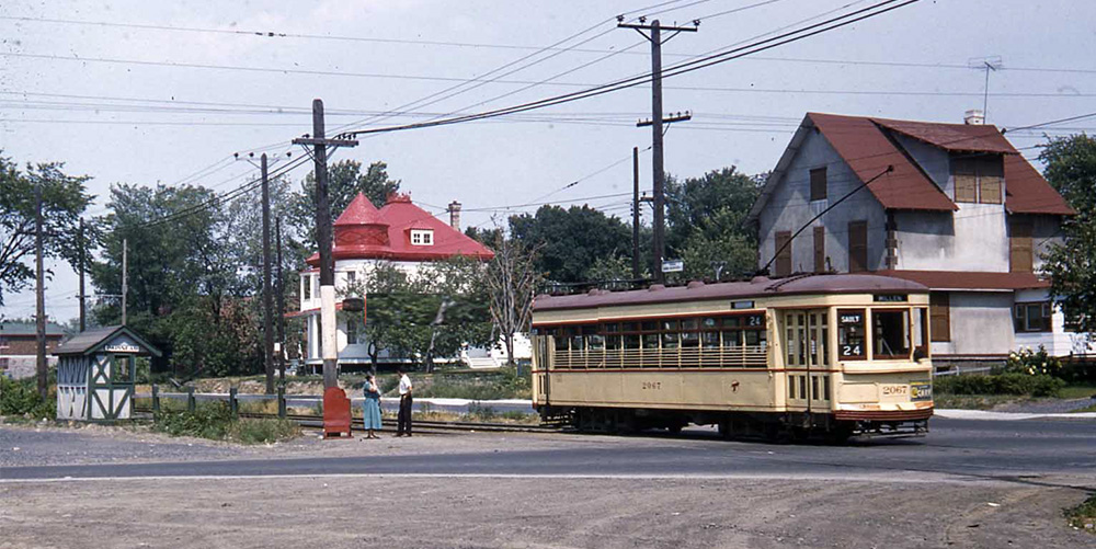 À la gauche de la photo, la cabine d’attente du tramway au sud du boulevard Gouin à l’intersection de l’avenue Papineau. Un tramway de la ligne 24 Millen-Sault passe devant deux maisons aujourd’hui disparues. 