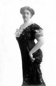 Photo en noir et blanc d'une femme portant une robe d'opéra à manches courtes, typique du début du 20e siècle.
