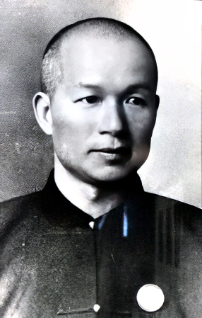 Photo d'un portrait tête et épaules en noir et blanc d'un jeune homme chinois aux cheveux coupés très court, rasé de près, portant une veste sans col de couleur sombre de style chinois.