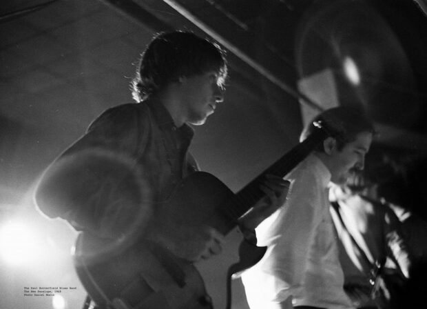 Deux membres du Paul Butterfield Blues Band apparaissent sur une photographie en noir et blanc prise de près sur le côté de la scène