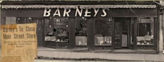 Façade d’un magasin avec de grandes vitrines et une porte ornée d’un panneau où l’on peut lire « Barney’s ».