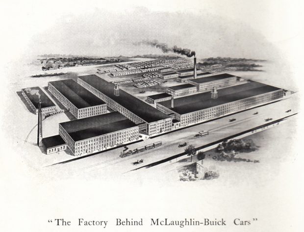 Un tableau en noir et blanc décrivant une usine constituée de neuf petits bâtiments et quatre grands. Les bâtiments sont situés près de lignes de chemin de fer et de nombreux conteneurs de fret. On voit deux cheminées. La légende indique L’usine qui produit les voitures McLaughlin-Buick 