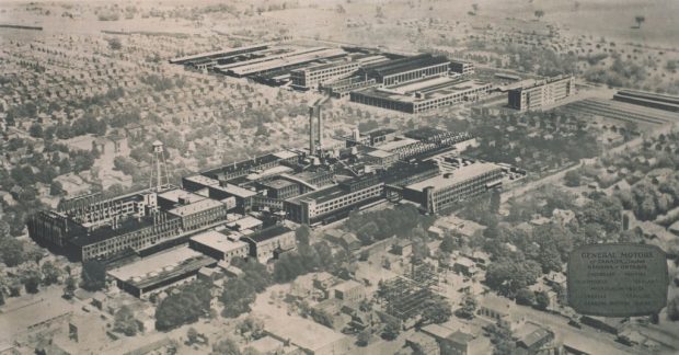 Une photo aérienne d’une série de bâtiments d’usine. La photo a été retouchée pour faire ressortir les bâtiments par rapport à l’arrière-plan.