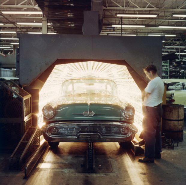 Un homme regarde une voiture des années 50 passer dans un énorme four industriel.