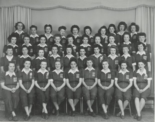 Quarante femmes en combinaison une-pièce posent pour une photo de groupe.