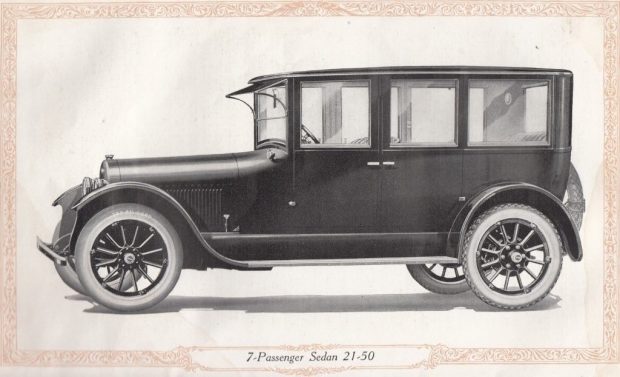  Un tableau en noir et blanc représentant une automobile. Le véhicule a un pavillon carré, des marchepieds et des pneus à flancs blancs. La légende indique Berline 7 passagers 21-60 