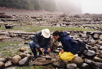 Graham Beard et un paléontologue amateur, accroupis l’un à côté de l’autre, en train d’examiner une fissure dans une roche.