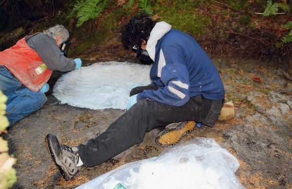  Graham Beard et Rob Bartlett, accroupis dans le lit du ruisseau, appliquant du fibre de verre à l’empreinte.