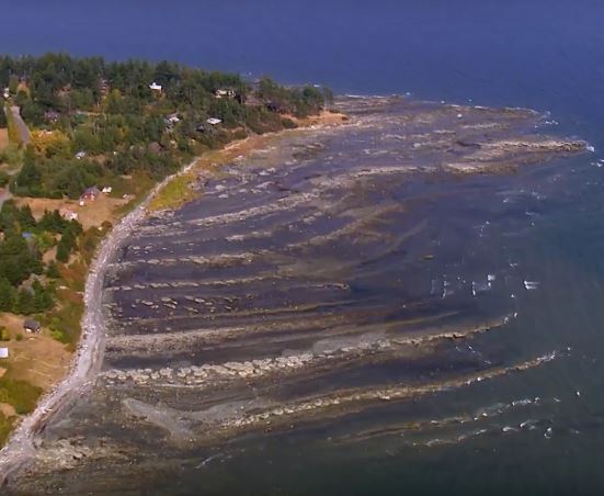 Une vue aérienne d'un littoral aux arêtes rocheuses qui s'étendent dans la mer.