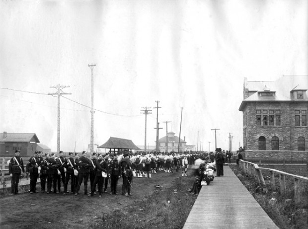 Soldats se tenant à gauche d'un trottoir en bois à gauche de l'édifice administratif.