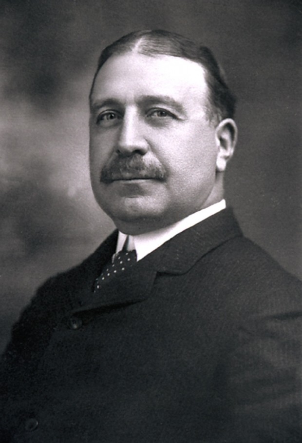 Portrait en noir et blanc de Francis Clergue, en habit noir et cravate. Il porte une moustache et ses cheveux très foncés sont séparés au centre.